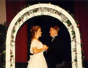 A man and a woman being married under an arch.